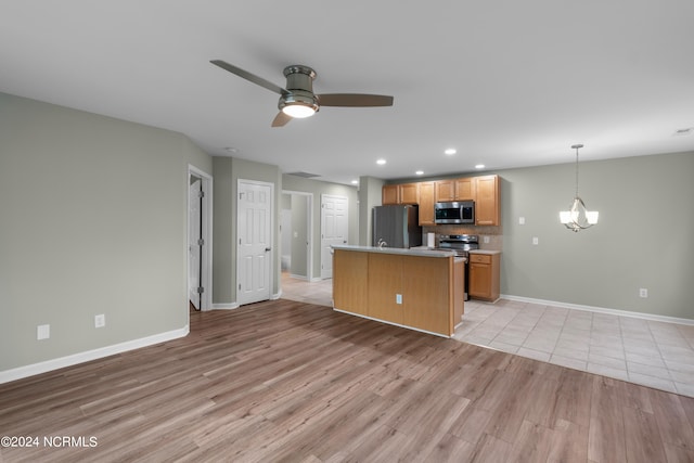 kitchen featuring a center island, ceiling fan with notable chandelier, appliances with stainless steel finishes, decorative light fixtures, and light hardwood / wood-style floors