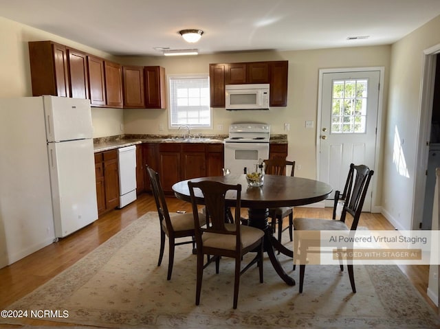 kitchen featuring light wood-style flooring, white appliances, a sink, visible vents, and baseboards