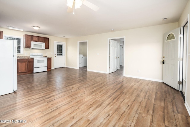 unfurnished living room featuring ceiling fan, light wood finished floors, washer / dryer, and baseboards