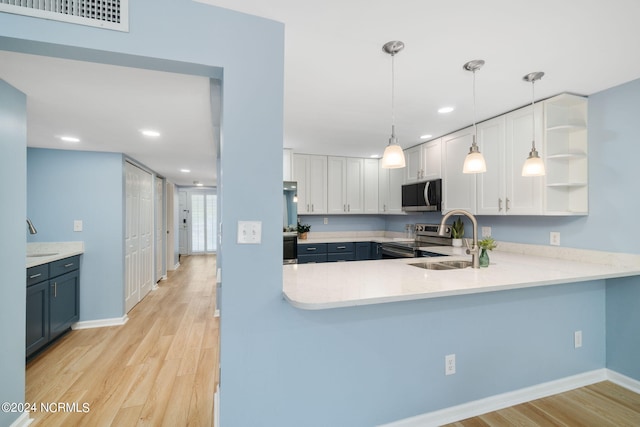 kitchen with sink, decorative light fixtures, appliances with stainless steel finishes, kitchen peninsula, and white cabinets