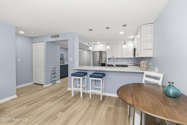 331 Salter Path Rd Unit 104, Pine Knoll Shores, NC 28512 - kitchen with appliances with stainless steel finishes, a sink, open shelves, light wood-type flooring, and a peninsula