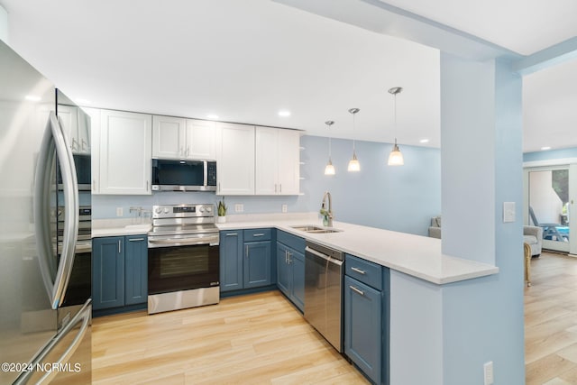 kitchen featuring sink, hanging light fixtures, light wood-type flooring, kitchen peninsula, and stainless steel appliances