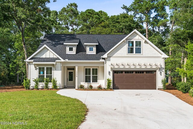 view of front of home with a front yard, a garage, and a porch