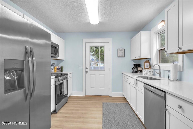 kitchen featuring a textured ceiling, sink, white cabinetry, and stainless steel appliances