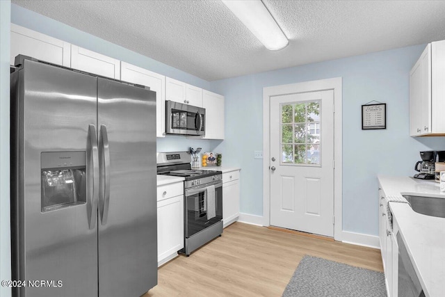 kitchen featuring light stone countertops, light wood-type flooring, a textured ceiling, stainless steel appliances, and white cabinetry