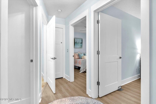 corridor featuring a textured ceiling and light wood-type flooring