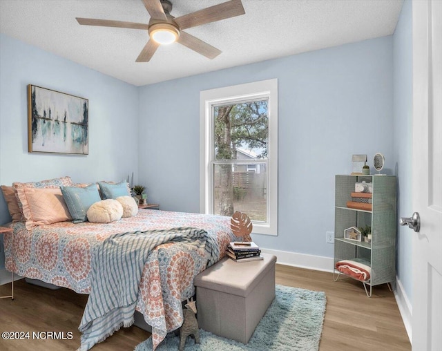 bedroom with multiple windows, hardwood / wood-style floors, a textured ceiling, and ceiling fan