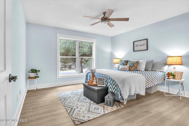 bedroom with wood-type flooring, a textured ceiling, and ceiling fan