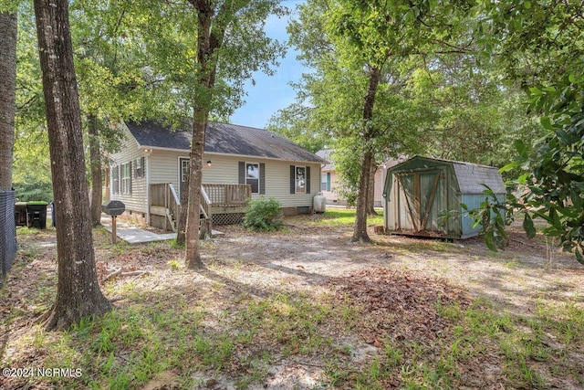 rear view of property with a wooden deck and a shed