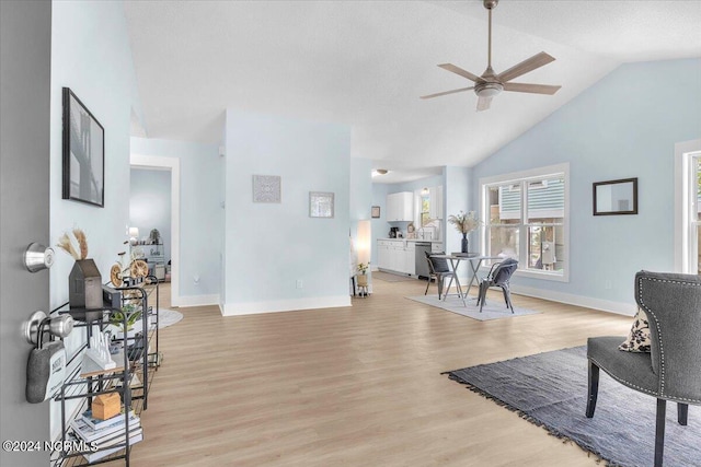 living room with ceiling fan, light hardwood / wood-style floors, and lofted ceiling