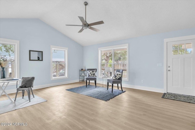 sitting room with ceiling fan, vaulted ceiling, a textured ceiling, and light hardwood / wood-style flooring