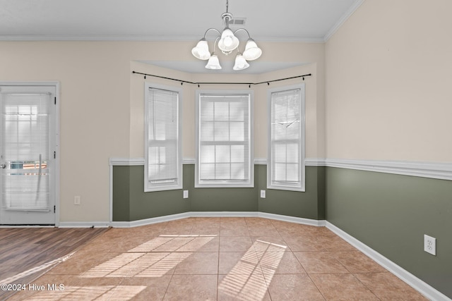 unfurnished dining area featuring ornamental molding, light tile patterned floors, and a chandelier