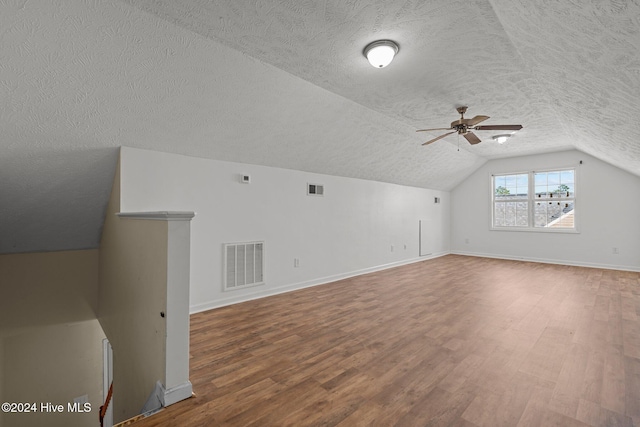 additional living space featuring a textured ceiling, hardwood / wood-style flooring, ceiling fan, and lofted ceiling