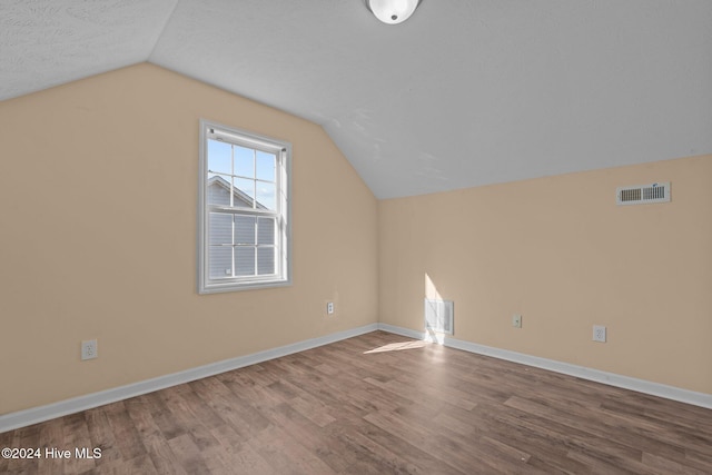 bonus room with hardwood / wood-style floors, lofted ceiling, and a textured ceiling