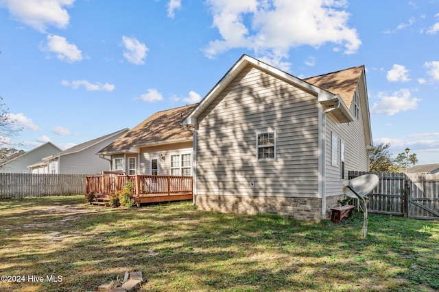 back of property featuring a deck and a lawn