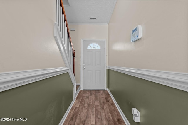 entryway with wood-type flooring, a textured ceiling, and ornamental molding