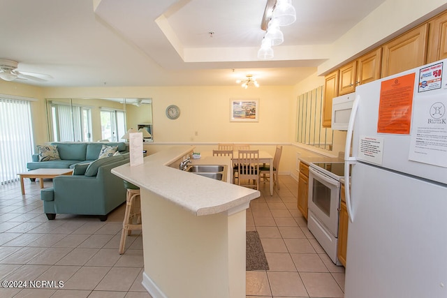 kitchen with sink, light tile patterned flooring, a breakfast bar area, and white appliances