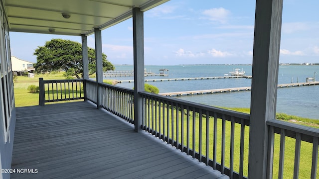 wooden terrace with a water view and a lawn