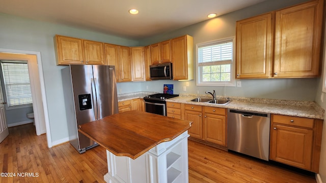 kitchen featuring light stone countertops, sink, appliances with stainless steel finishes, and light hardwood / wood-style flooring