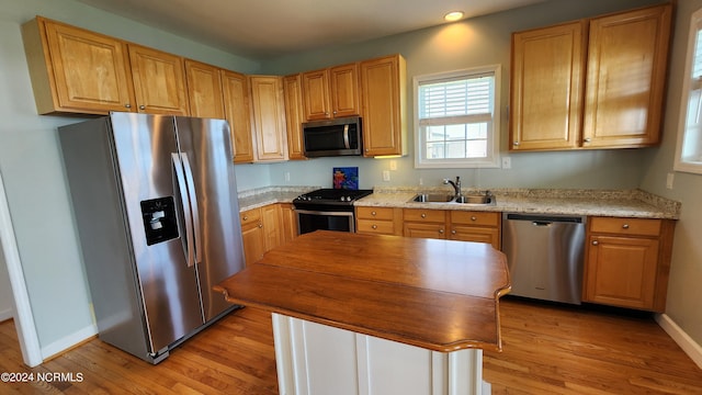 kitchen with light stone countertops, sink, light hardwood / wood-style flooring, and appliances with stainless steel finishes