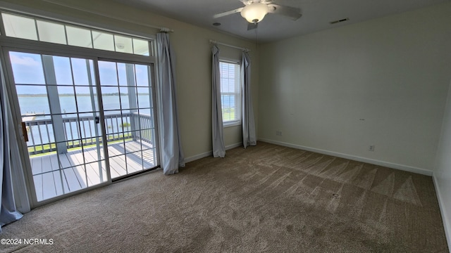 carpeted empty room featuring ceiling fan and a water view