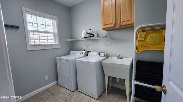 laundry area featuring washer and clothes dryer, light tile patterned floors, and cabinets