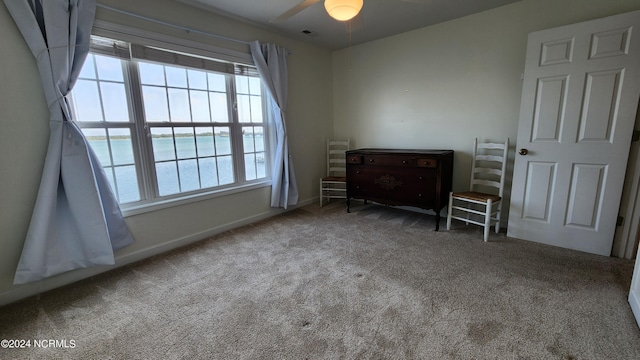 bedroom with carpet, ceiling fan, and a water view