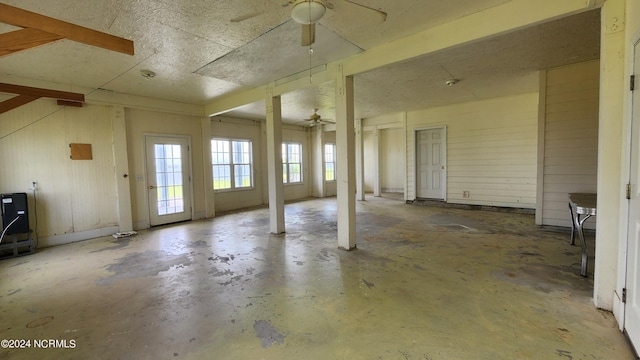 miscellaneous room featuring concrete flooring, ceiling fan, and wood walls