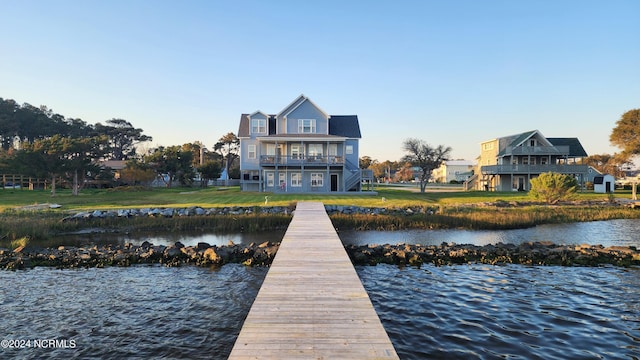 dock area with a water view, a yard, and a balcony