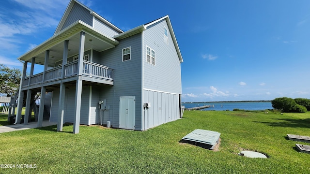 view of property exterior with a balcony, a yard, and a water view