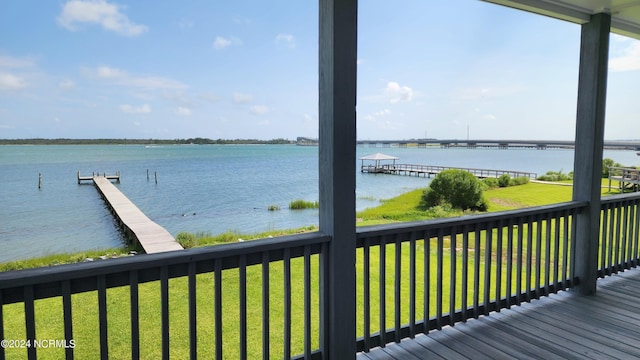 deck with a yard, a water view, and a dock