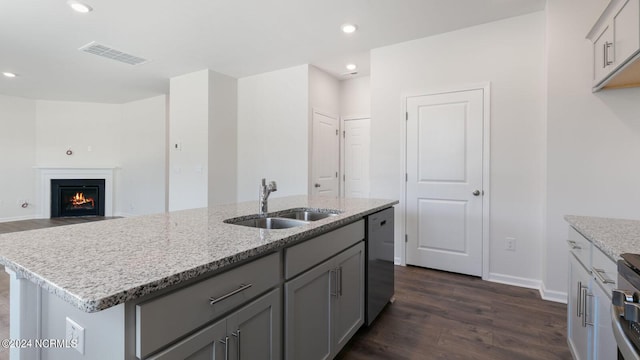 kitchen with a center island with sink, sink, stainless steel dishwasher, gray cabinets, and dark hardwood / wood-style flooring