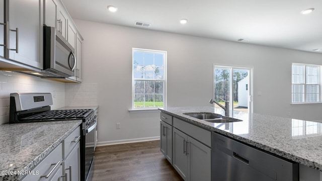 kitchen featuring dark wood-type flooring, sink, decorative backsplash, light stone counters, and stainless steel appliances