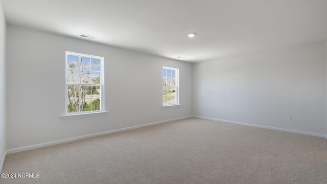 empty room with light colored carpet and a healthy amount of sunlight