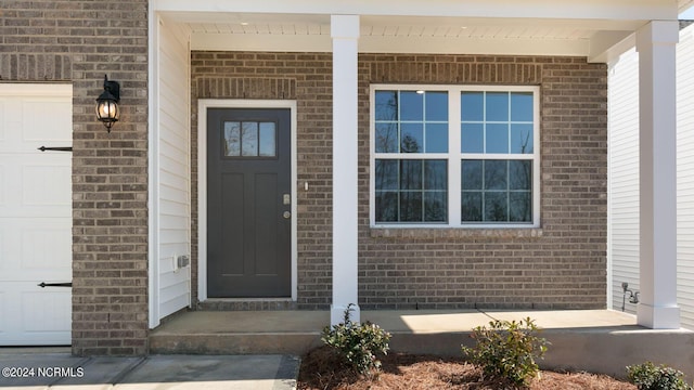 entrance to property featuring a porch and a garage