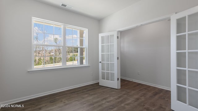 empty room with plenty of natural light, dark wood-type flooring, and french doors