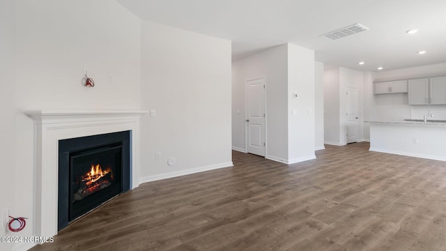 unfurnished living room featuring sink and dark wood-type flooring