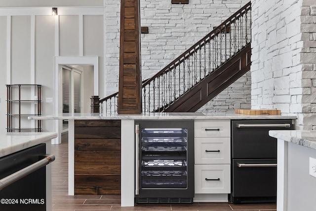 bar featuring light stone counters, white cabinetry, black dishwasher, and wine cooler