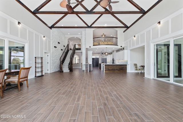 living room featuring beamed ceiling, ceiling fan, and a high ceiling