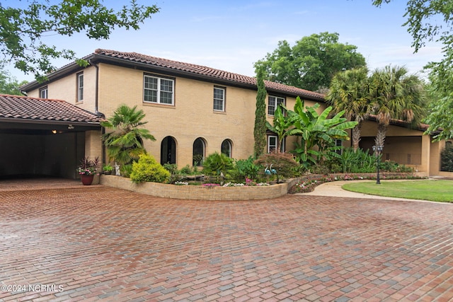 mediterranean / spanish house with a tile roof, decorative driveway, and brick siding