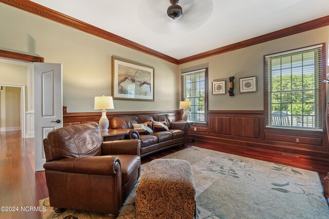 living room with a wainscoted wall, ceiling fan, wood finished floors, and crown molding