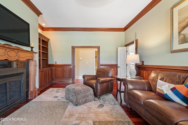 living area featuring wainscoting, crown molding, a tiled fireplace, and wood finished floors