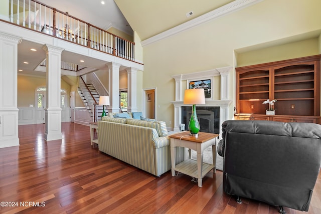 living room with decorative columns, ornamental molding, high vaulted ceiling, a premium fireplace, and dark hardwood / wood-style floors