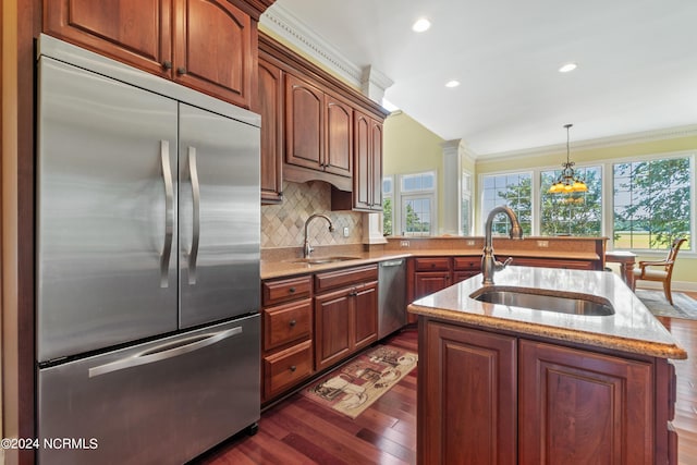 kitchen with decorative backsplash, appliances with stainless steel finishes, a kitchen island with sink, and sink