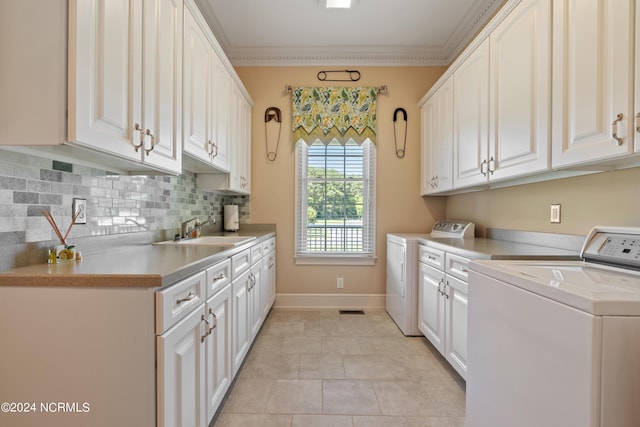 laundry area featuring cabinet space, baseboards, ornamental molding, washing machine and dryer, and a sink