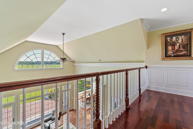 hall with wainscoting, lofted ceiling, ornamental molding, wood finished floors, and a decorative wall