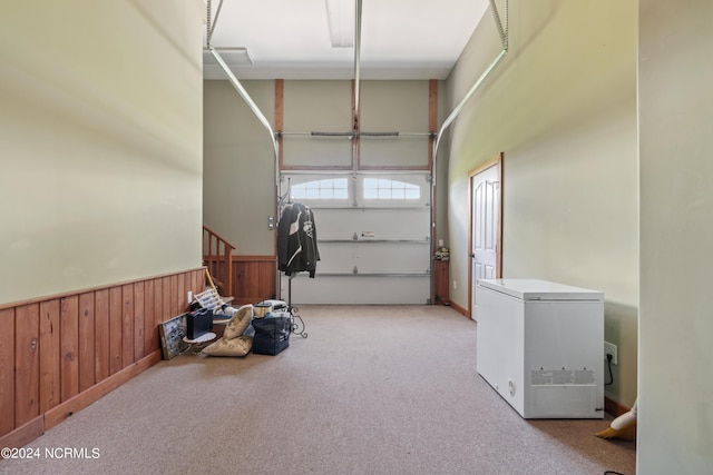 garage featuring wooden walls, wainscoting, and refrigerator