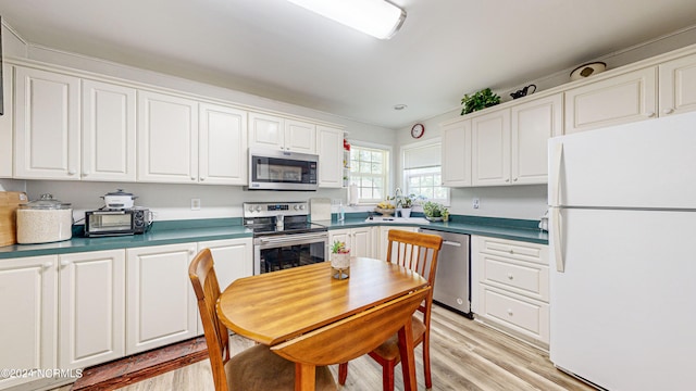 kitchen with white cabinets, light wood-type flooring, and stainless steel appliances