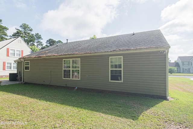 rear view of house with cooling unit and a yard