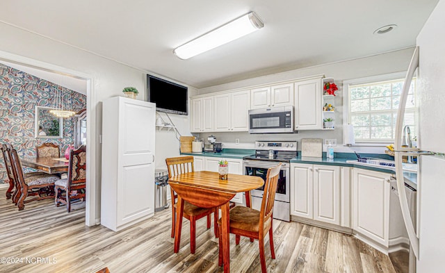 kitchen featuring light hardwood / wood-style flooring, white cabinetry, and stainless steel appliances